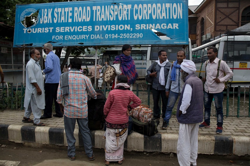 Men stand in front of a transport sign.