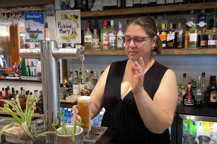 A woman puring a beer behind a bar