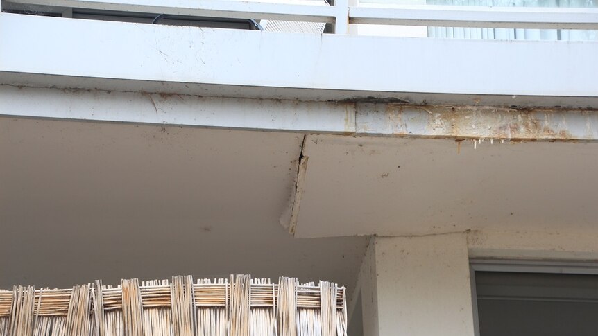 A cracked, sagging balcony seen from below.