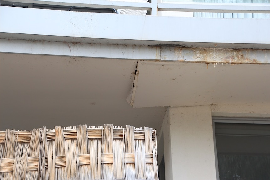 A cracked, sagging balcony seen from below.