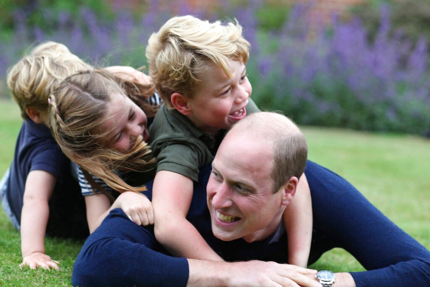 Prince William plays with his family on a lawn
