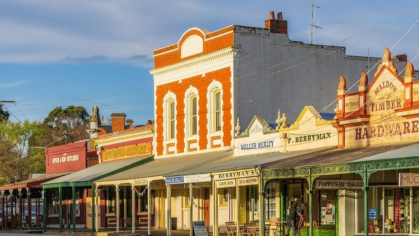 Old wooden and red brick historical looking buildings stand lined on a street.