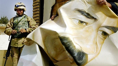 A US Marine pulls down a poster of Iraqi President Saddam Hussein March 21, 2003 in Safwan, Iraq.