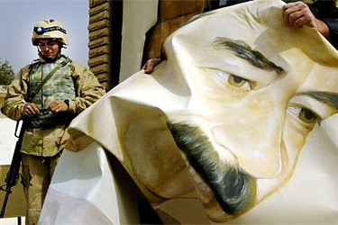 A US Marine pulls down a poster of Iraqi President Saddam Hussein March 21, 2003 in Safwan, Iraq.