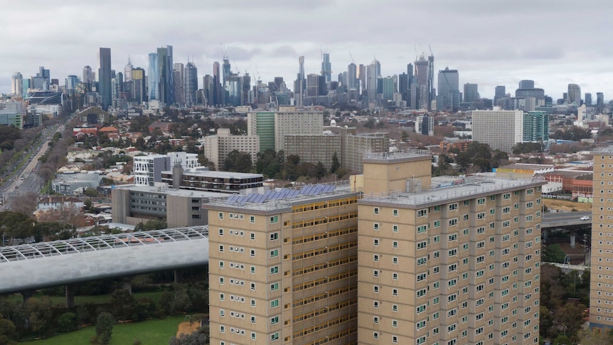 Two public housing towers can be seen with the Melbourne city skyline in the background.