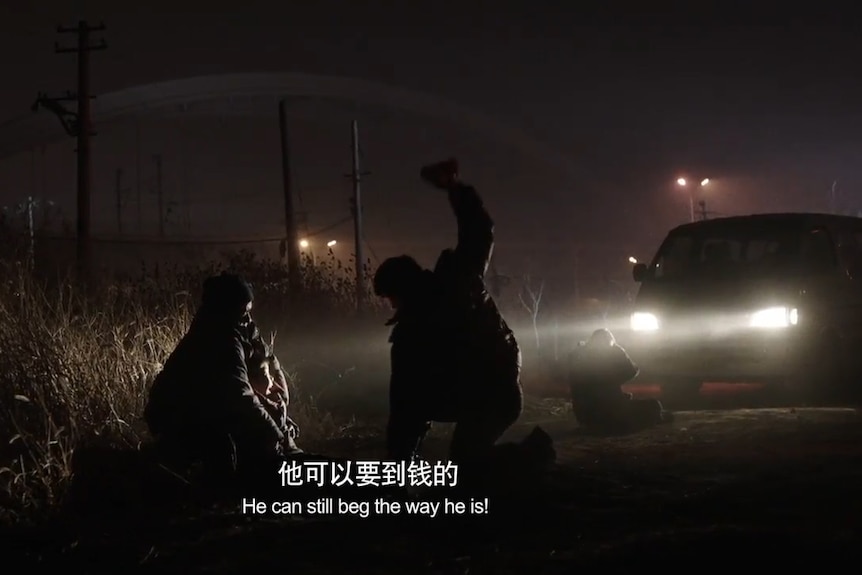 A screenshot from a film shows a confrontation on the side of a dark road.