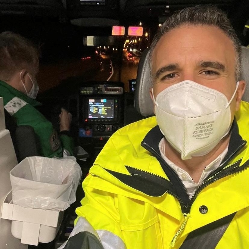 man in jacket with mask in the back of an ambulance