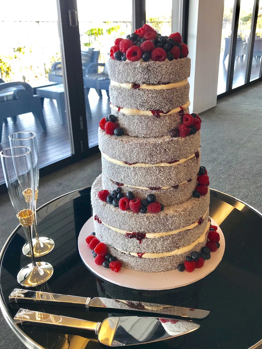 A three tiered wedding cake of lamingtons with cream and berries for a story about lamington's history and baking tips.