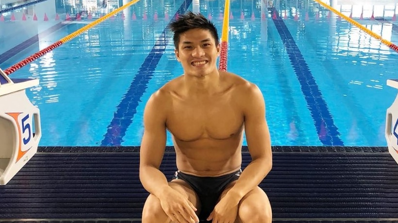 A swimmer sitting in front of a pool.