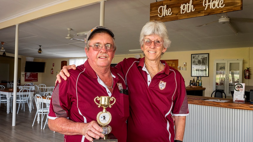 A man and woman stand holding a small trophy.