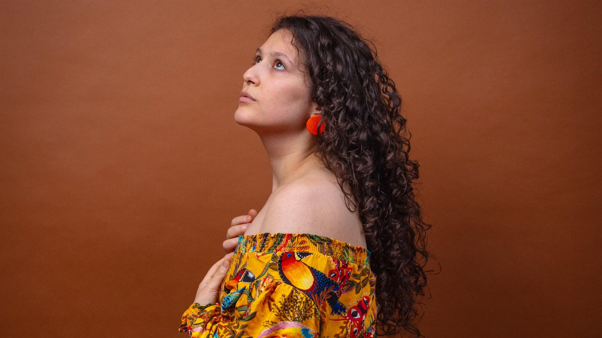 Singer Jamile in a colourful dress standing on her side 