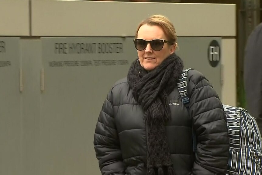 Leanne Reid wears sunglasses and a puffer jacket as she walks from court.