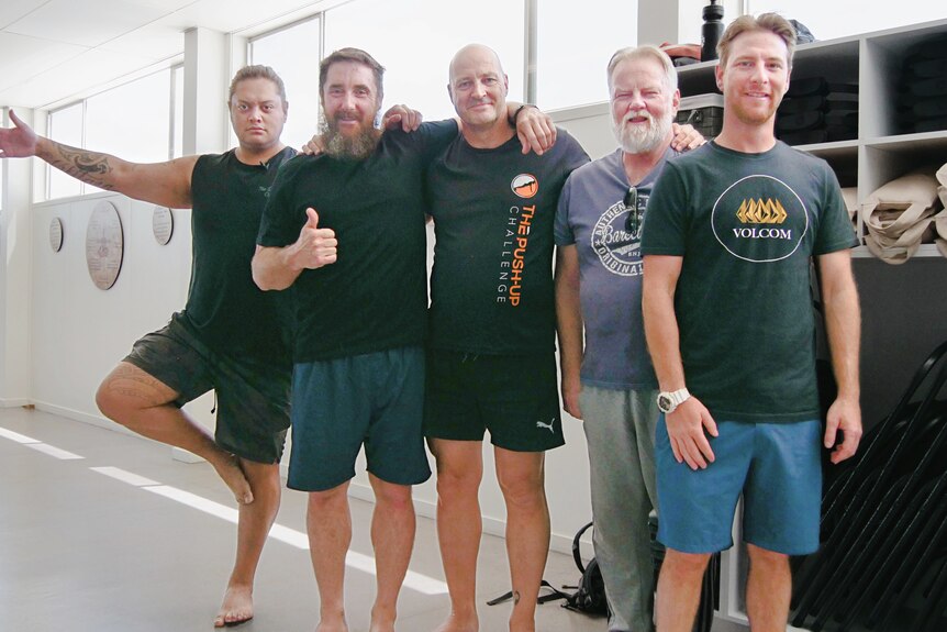 a group of men smiling in a yoga studio