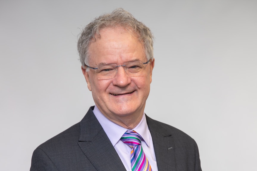 man in suit and glasses smiles into camera