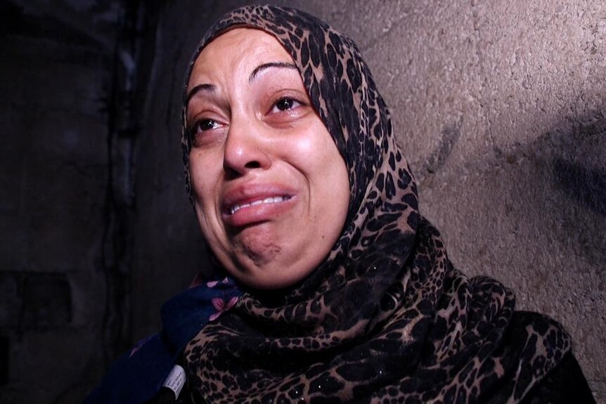 Fida Mosabeh cries as she talks to the ABC inside her Gaza home.