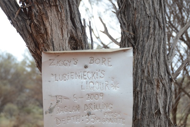 A metal sign reporting the location of a water bore in the outback.