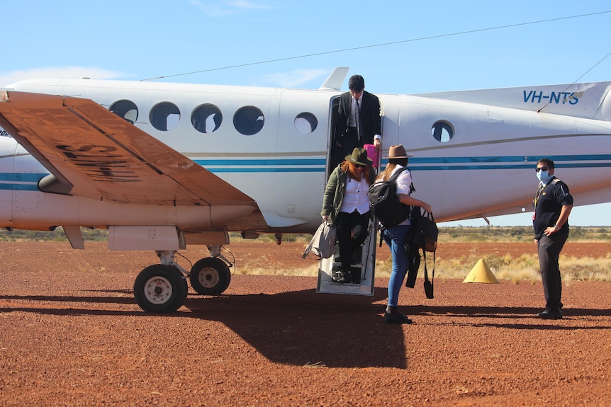 People alight from a small plane in the desert