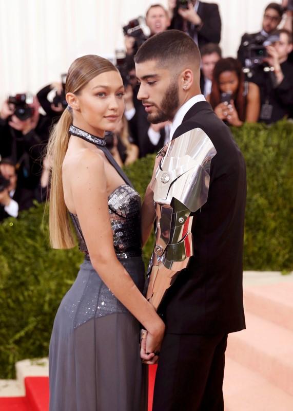 A man and woman pose together in formal wear on a red carpet