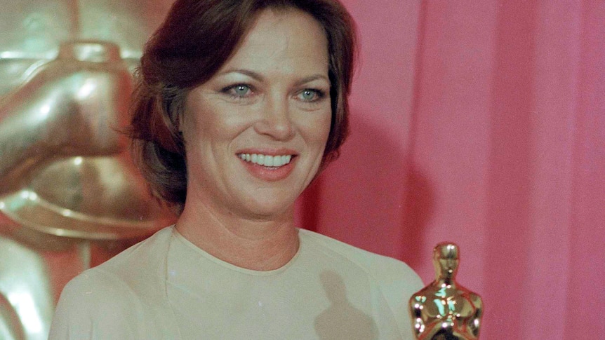 A woman smiles as she hold her Academy Award Oscar