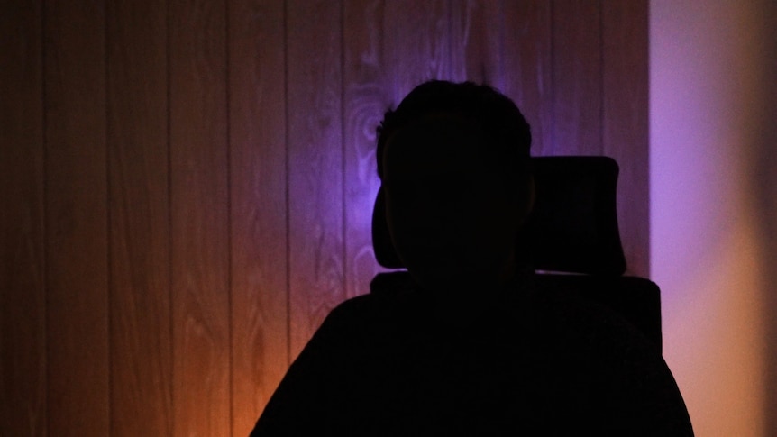 A man sitting on a chair in silhouette to hide his face and identity