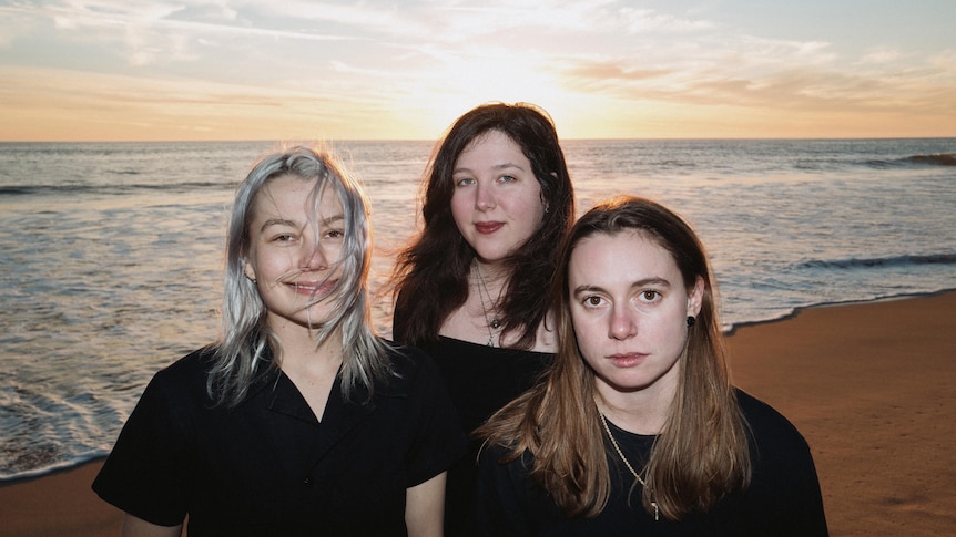 Phoebe Bridgers, Lucy Dacus and Julien Baker stand on an empty beach wearing black