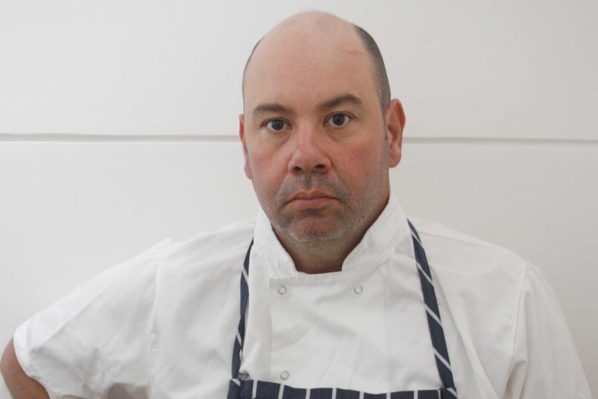 Edward Seisun, wearing an apron, faces the camera.