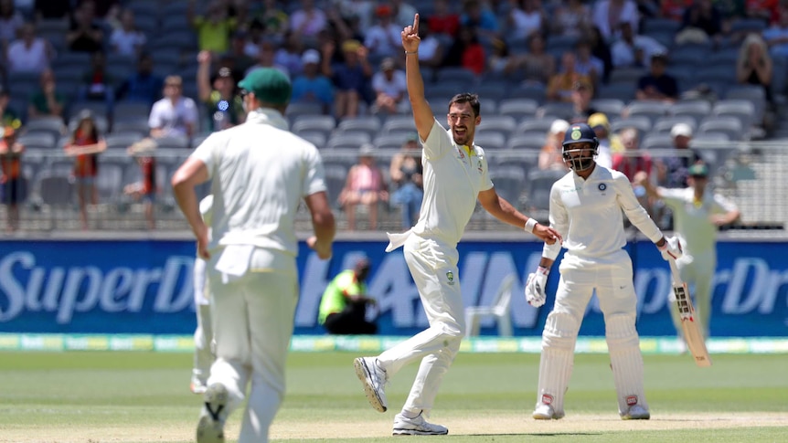 Smiling Australian bowler Mitchell Starc points to the sky during a Test as Indian batsman Hanuma Vihari looks on.