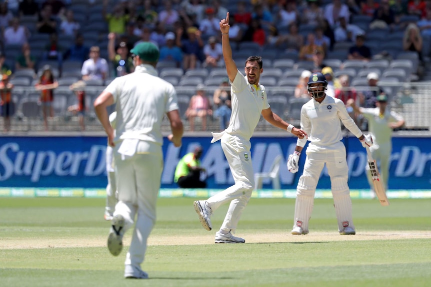 Smiling Australian bowler Mitchell Starc points to the sky during a Test as Indian batsman Hanuma Vihari looks on.