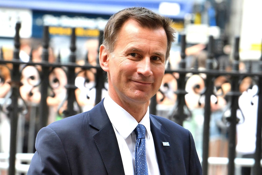 A head and shoulders image of Jeremy Hunt smiling while standing on a street.