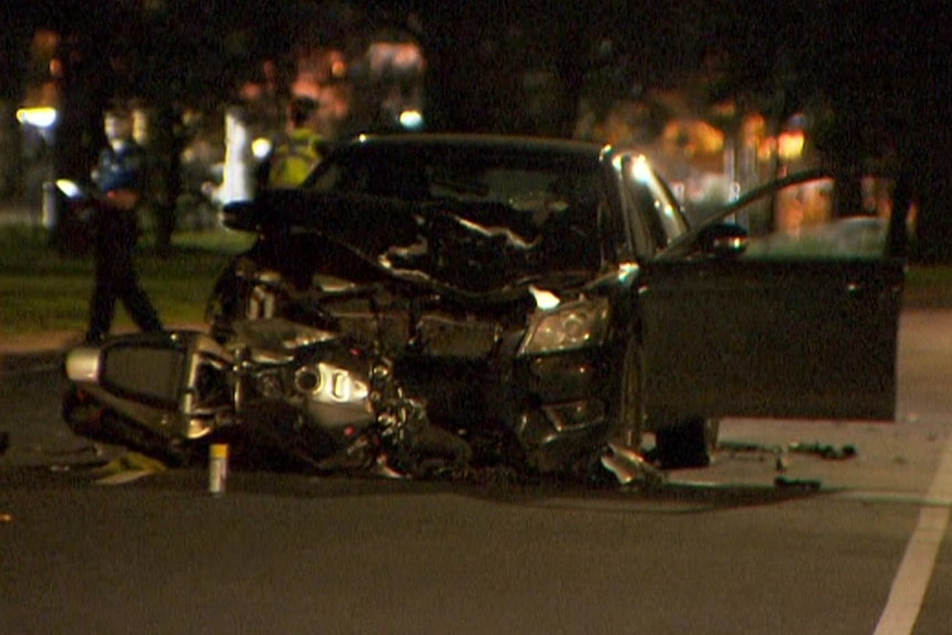 A motorcycle on its side in front of a damaged black car