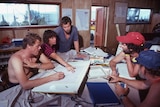 a group of people sit around a table looking at maps