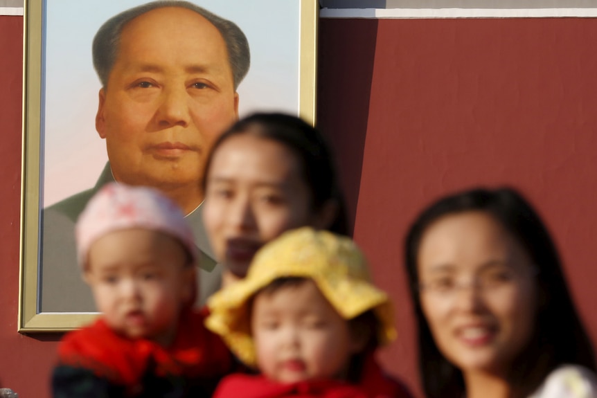  Two women and their babies pose for photographs in front of the giant portrait of late Chinese chairman Mao Zedong