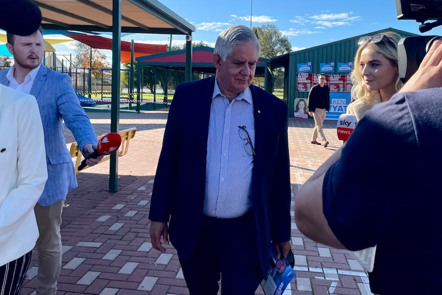 Ken Wyatt wearing a suit and surrounded by the media at Ellenbrook Primary School.