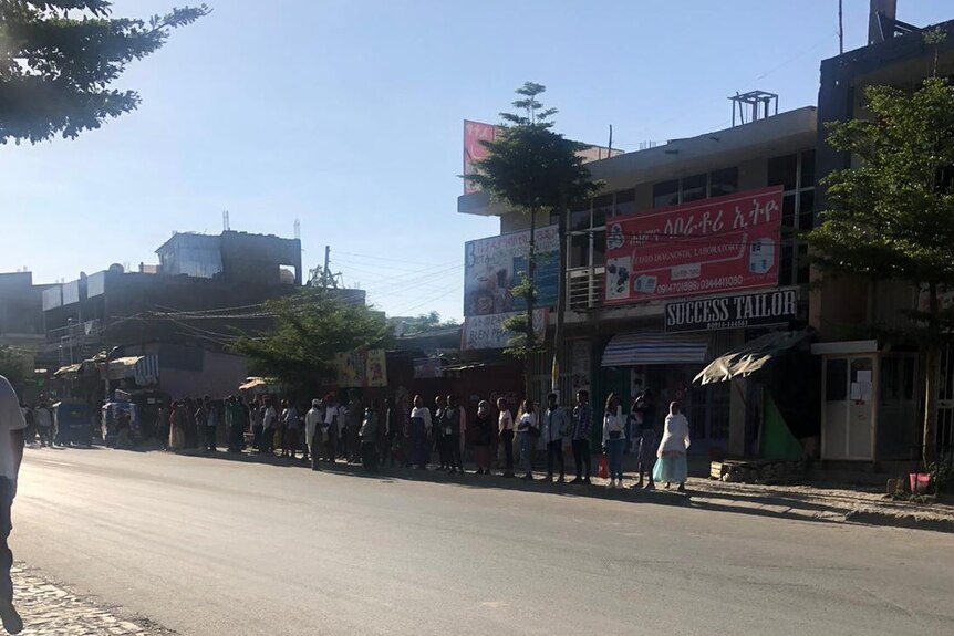 Dozens of people queue down the street waiting to buy goods in the Tigray region of Ethiopia
