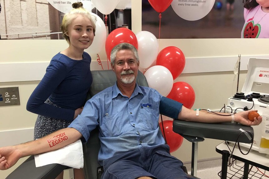 Llewellyn Markey stands by her father who is hooked up to a blood donation apparatus.