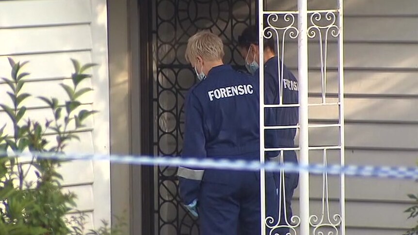 Two forensic offices go in the front door of  house in Mitcham, where a body was found.