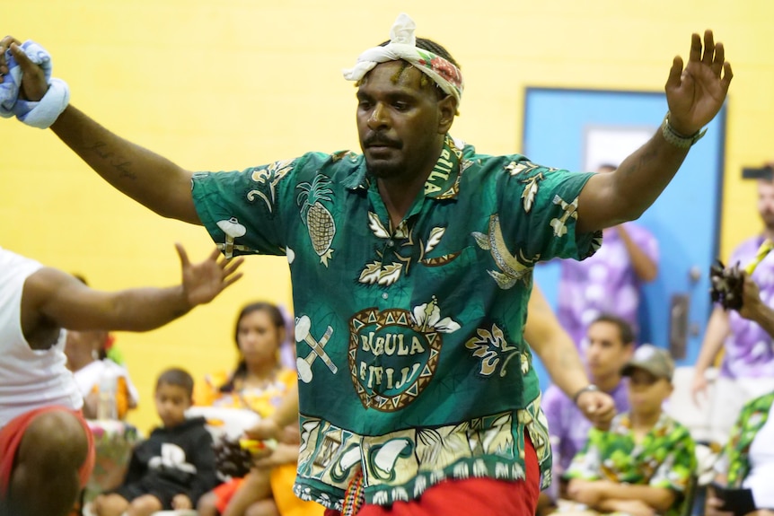 Man in green island shirt with hands wide open dancing