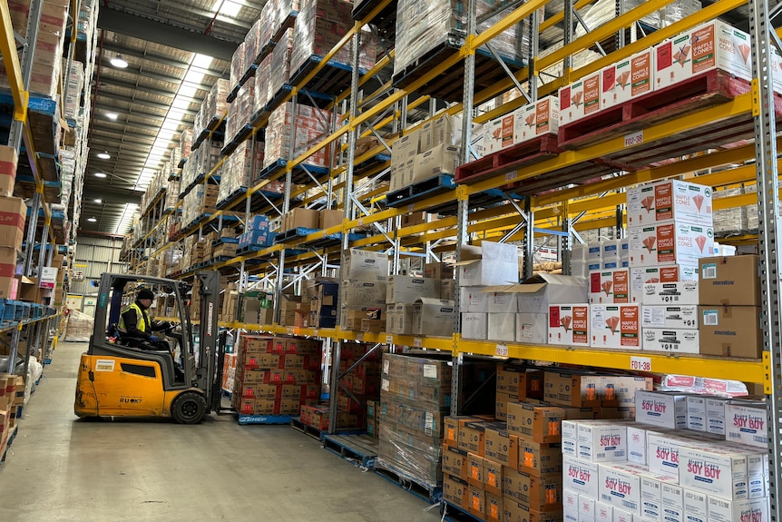 A forklift moves a pallet of goods in a large warehouse
