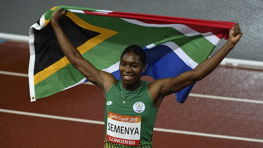 South African runner Caster Semenya lifts a flag behind her head after winning race.