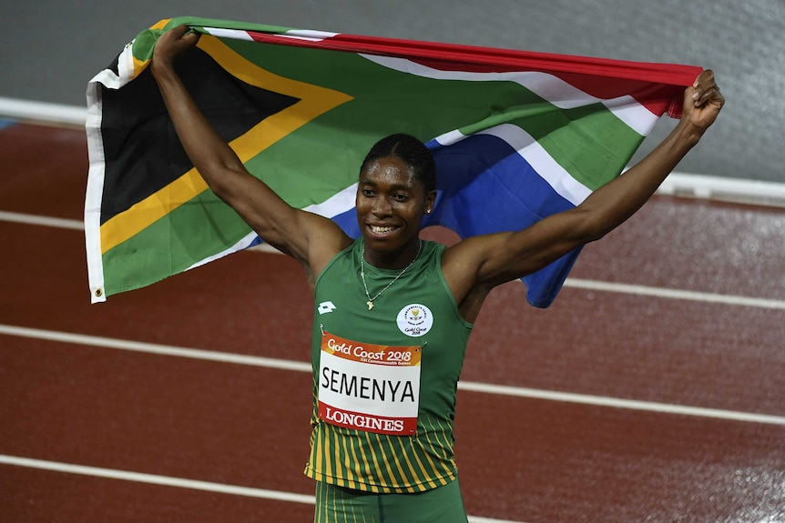 South African runner Caster Semenya lifts a flag behind her head after winning race.