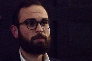 A man with a dark beard and glasses.