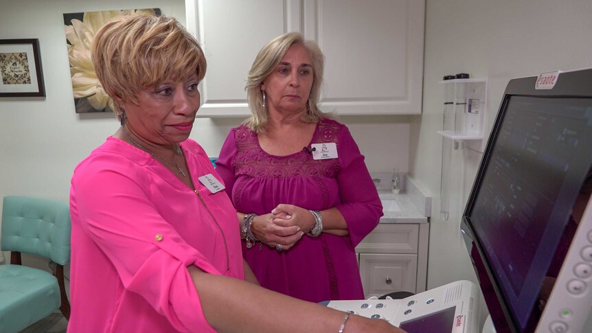 Two women inspect an ultrasound machine