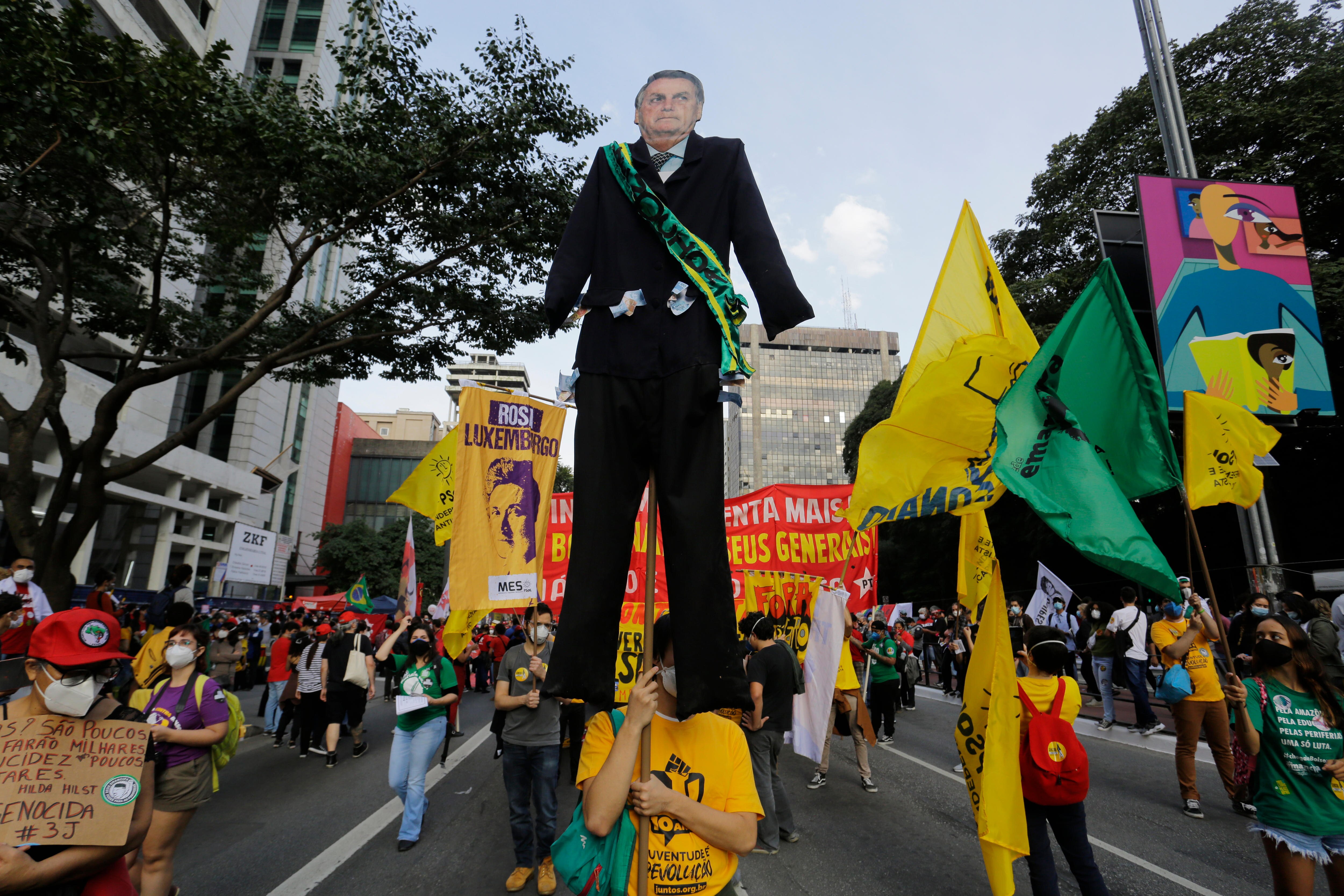 Woman marches in protest carrying large cutout photo of Jair Bolsonaro 