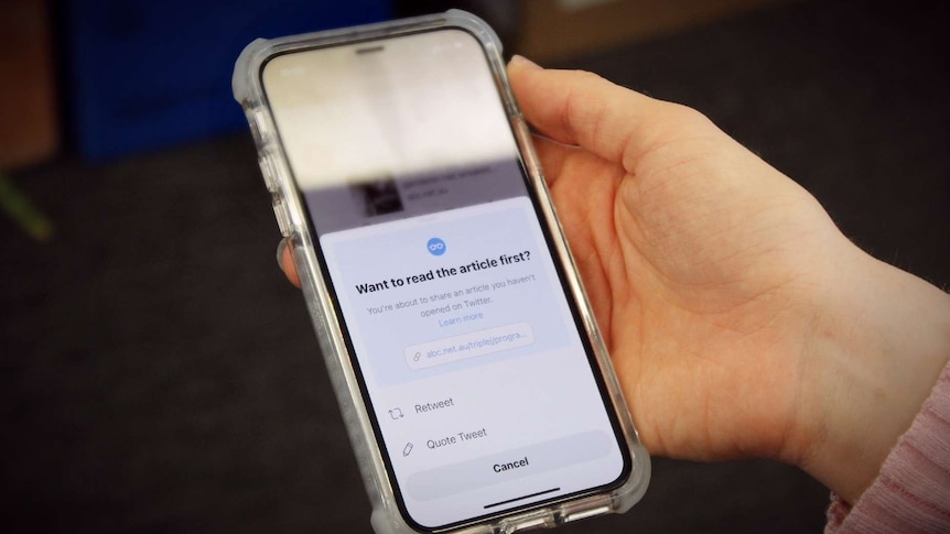 A woman holds a phone displaying an app interface