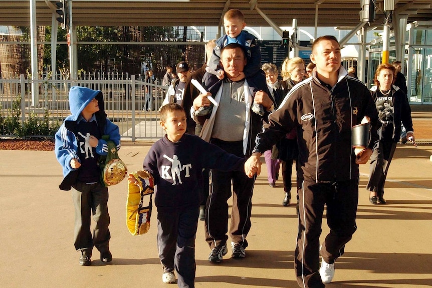Tim Tszyu holds his father's hand after he arrives back in Australia after successfully defending his world title in 2002.