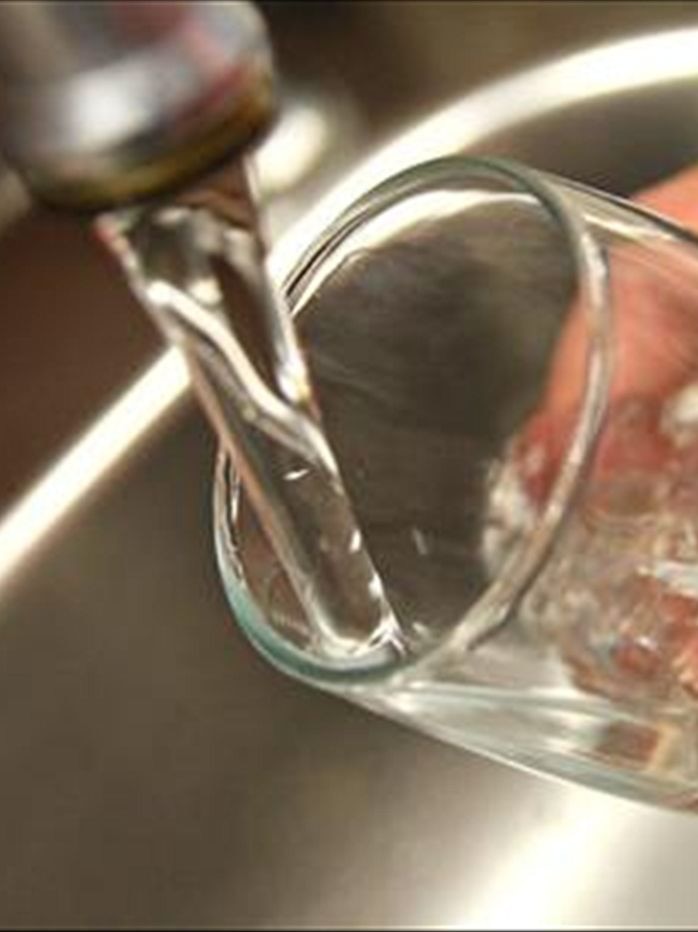 Water pours from a tap into a glass.