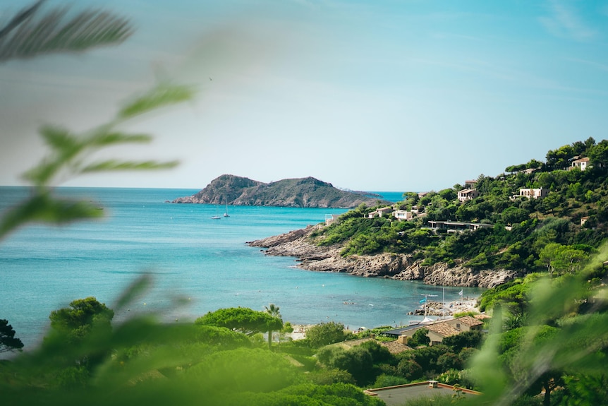 A photo of blue ocean with green mountains surrounding it