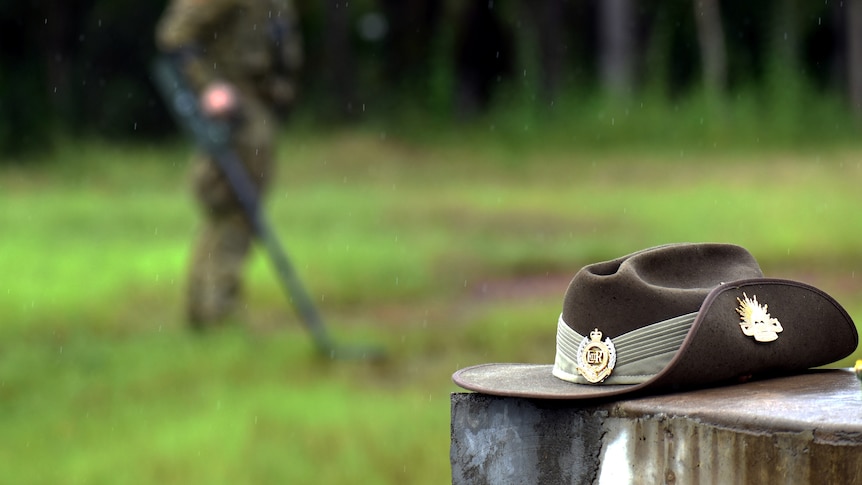 A solider in the background performing their task while a slouch hat is present in the foreground.