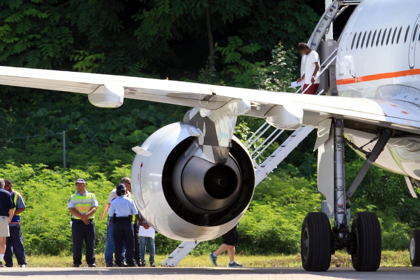 Asylum seekers step from a plane on Nauru after arriving from Christmas Island.