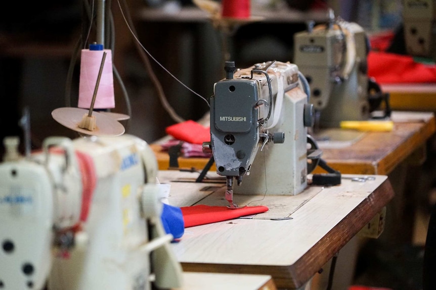 A sewing machine sits on a bench in a workshop